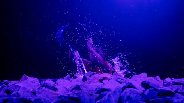 Mężczyzna polewa rozgrzane kamienie wodą.