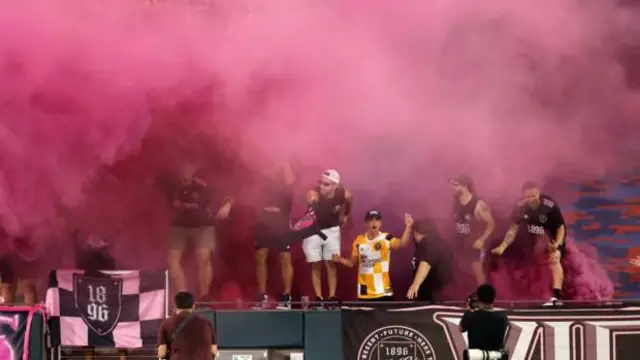 Torcedores no meio de fumaça rosa