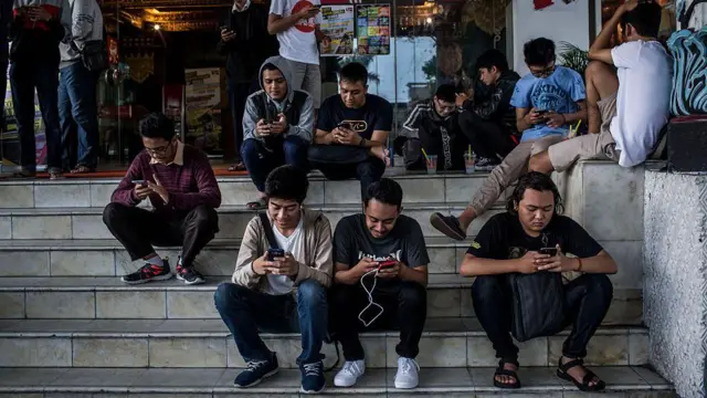 Sejumlah orang sedang memainkan ponsel pintranya di depan gerai makanan di Yogyakarta, pada 23 Juli 2016. 