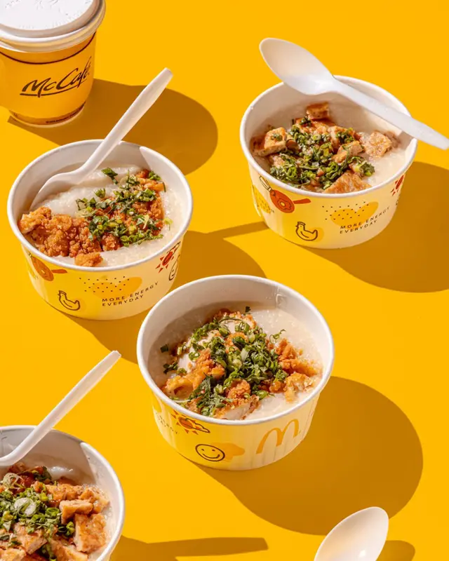 Картонні тарілки з кашею та шматками мʼяса в паніровці на жовтому тлі