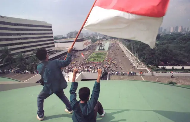 Mahasiswa berdiri di atap gedung parlemen mengibarkan bendera Indonesia saat mereka menuntut pengunduran diri presiden Soeharto 20 Mei 1998 di Jakarta, Indonesia