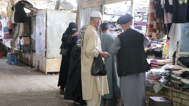 یوه مېرمن درې سړي یوه دوکان مخې ته لیدل کېږي.