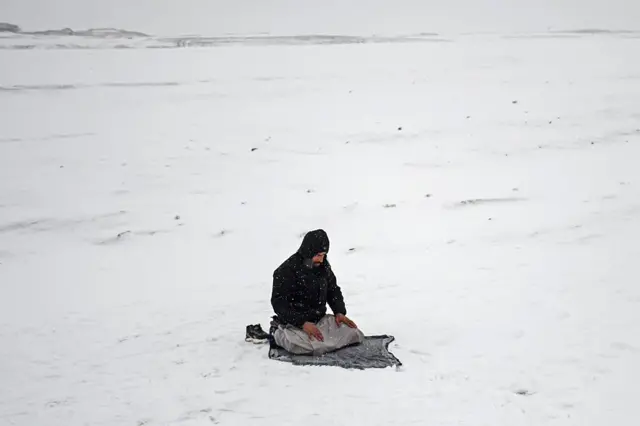 یو سړی د مزار شریف په یوه څنده کې لمونځ کوي