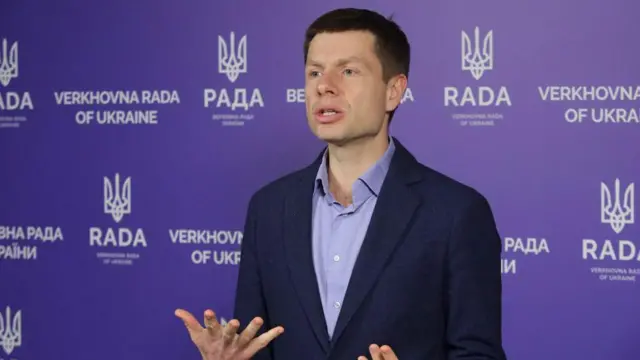 Гончаренко — мужчина в синей рубашке и темно-синем пиджаке на фоне надписей Рада и украинского герба