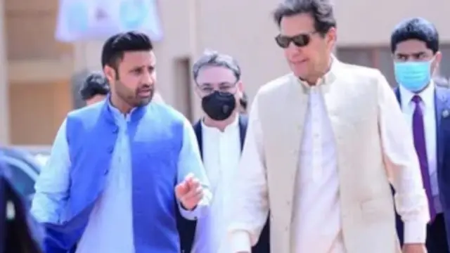 عکسی از عمران خان با لباس سفید و زلفی بخاری با لباس آبی کمرنگ و یک واسکت آبی پررنگ در حال راه رفتن