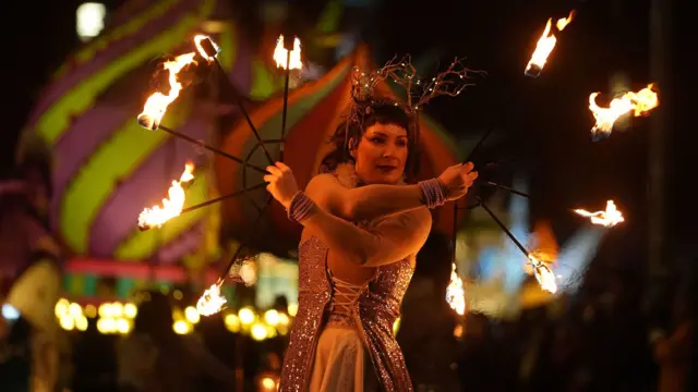 A street performer takes part in the Procession of Light in Dublin. She is holding  apparatus with fire on the end