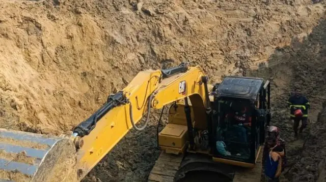 এক্সকাভেটোর দিয়ে মূল গর্তের চারপাশ থেকে মাটি খনন কাজ হচ্ছে। উৎসুক মানুষ তা দেখছে।