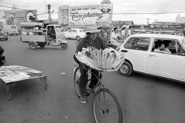 Một người đàn ông chở báo trên xe đạp trên đường phố Sài Gòn năm 1972