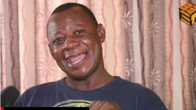 Abiodun Aremu to wọ asọ alawọ Buluu, ko de fila, o si n la ẹnu silẹ lati sọrọ.