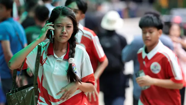 一名女學生在位於泰國曼谷郊外暖武里府挽粿縣（Bang Kruai）的帖詩琳暖武里學校校園內一邊步行一邊使用手機（7/8/2026）