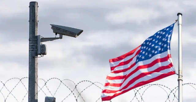 صورة لعلم الولايات المتحدة يرفرف أمام حاجز من الأسلاك (يبدو أن الصورة ملتقطة من الحدود)
