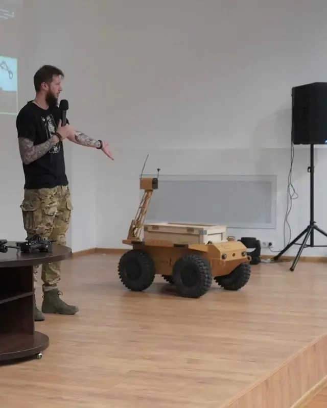 Військовий хлопець демонструє наземного робота на сцені