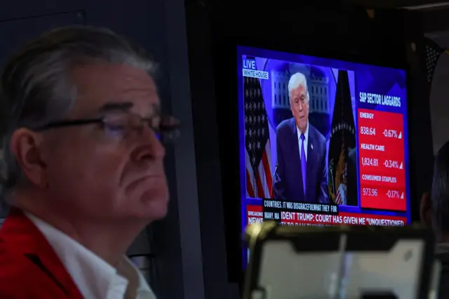 Operador da bolsa trabalha no pregão enquanto um telão exibe o presidente dos Estados Unidos, Donald Trump, durante uma entrevista coletiva sobre as tarifas