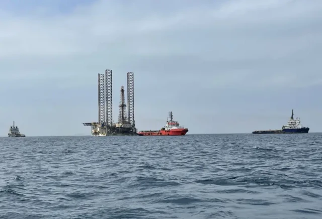 نمای دور از یک سکوی استخراج نفت در دریا و چند نفت کش در اطراف آن