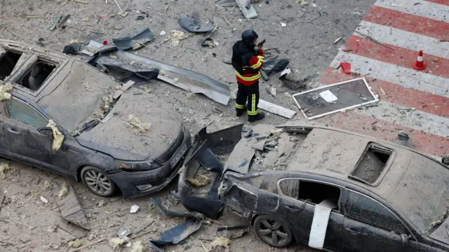 Пошкоджені і вкриті пилом авто, поруч із ними рятувальник 