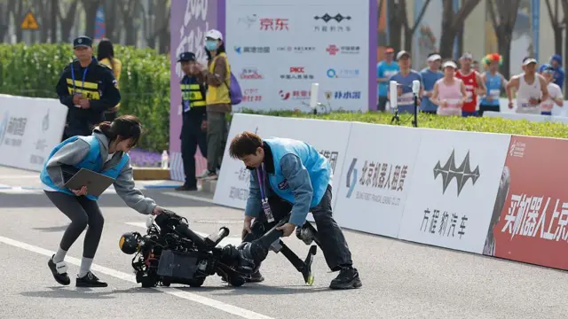 Техники оказывают помощь гуманоидному роботу, упавшему во время полумарафона в Пекине 19 апреля 2026 года 