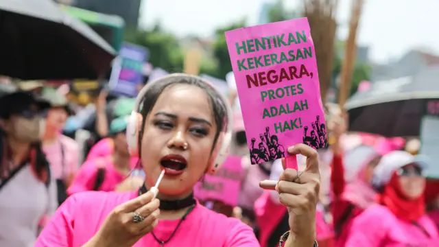 Salah seorang peserta aksi Aliansi Perempuan Indonesia membentangkan poster saat berunjuk rasa di depan kompleks DPR pada Rabu (3/9). 