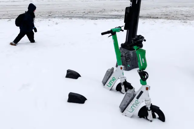 дете пролази кроз снег дубог до чланака, првом плану тротинети завејни снегом 