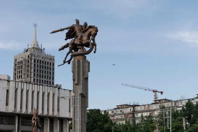 Герой эпоса «Манас» у здания филармонии в Бишкеке, на фоне идет строительство жилого комплекса Moscow city