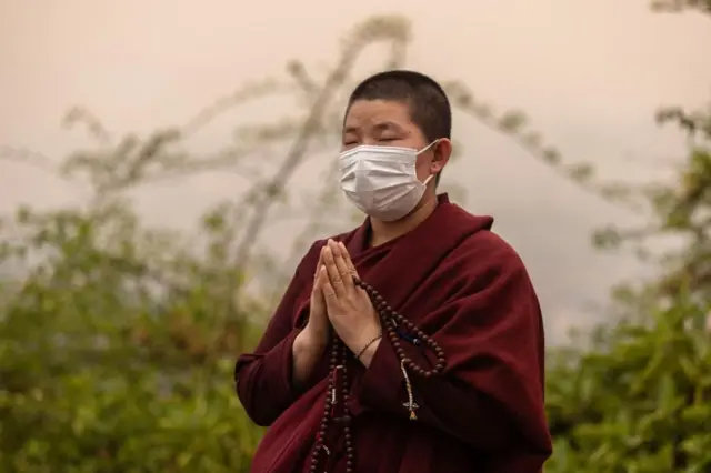 स्वयम्भूनाथमा मास्क लगाएर ध्यान गर्दै एक भिक्षुणी