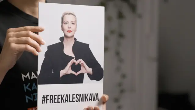 Татьяна Хомич, сестра Марии Колесниковой во время интервью показывает плакат с ее фото, где пальцы сложены в сердце, а также с хэштегом #FREEKALESNIKAVA 