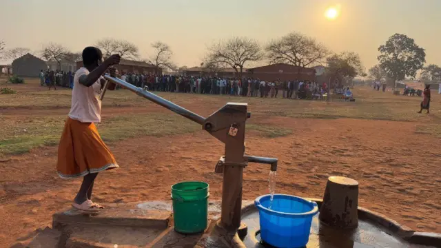 One girl wey wear school uniform dey fetch water, and pipo queue for distance to vote for Malawi elections