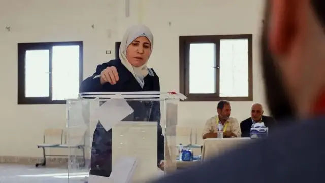 زنی در حال انداختن رای خود در صندوق رای