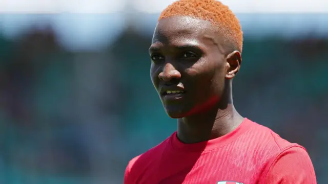 Temwa Chawinga est photographié en buste, les cheveux teints en orange, et porte un haut d'entraînement rouge.