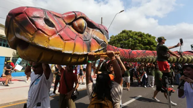  یک مار آناکوندا زیر آفتاب داغ از میان جمعیت عبور داده شد