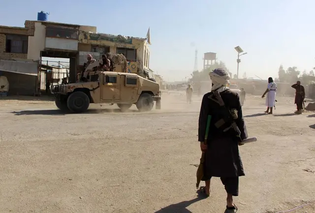 یک سرباز طالبان در منطقه مرزی اسپین بولدک. یک موتر هاموی نیروهای طالبان نیز در حال عبور از جاده است