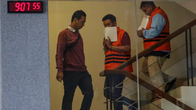 Kepala KPP Madya Jakarta Utara Dwi Budi (kanan) bersama Tim Penilai di KPP Madya Jakarta Utara Askob Bahtiar (tengah) menggunakan rompi tahanan usai menjalani pemeriksaan di Gedung Merah Putih KPK, Jakarta, Minggu (11/1/2026).