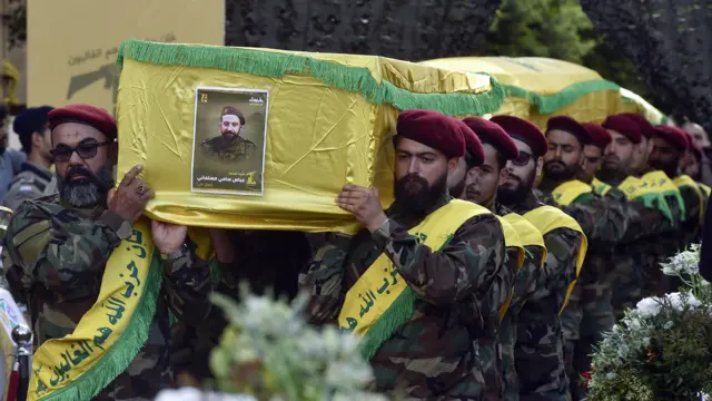 مقاتلون من حزب الله يحملون ثلاثة نعوش.