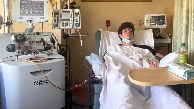 Um jovem deitado em uma cama de hospital fazendo exames