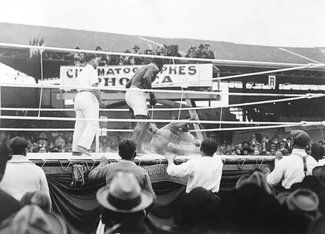 Carpentier au sol lors d'un combat contre Siki. Photo d'action du combat (entre Georges Carpentier et Siki).