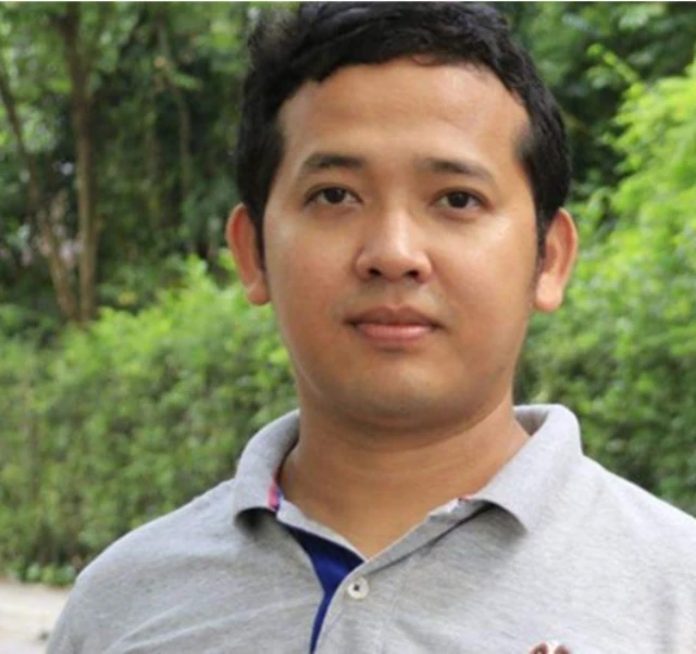 အေအေတပ်မှူးချုပ် ဗိုလ်ချုပ် ထွန်းမြတ်နိုင်ရဲ့ ညီ ဦးအောင်မြတ်ကျော်ကို ကင်မရာကိုကြည့်နေ။ ဆံပင်တိုတို မျက်နှာပြည့်ပြည့်နဲ့ သက်လတ်ပိုင်းအမျိုးသားဟာ မီးခိုးရောင် စပို့ရှပ်ကို ဝတ်ဆင်ထား 