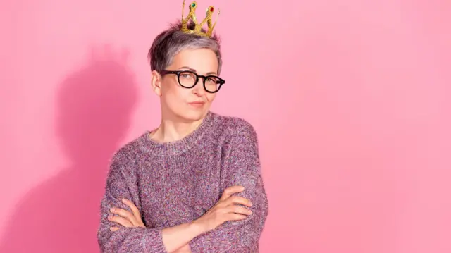 Приваблива жінка зрілого віку з коротким сивим волоссям і короною на голові