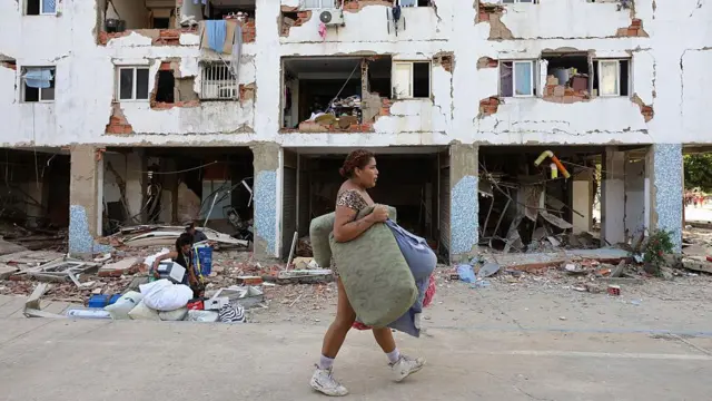 Una mujer pasa por delante de un edificio que sufrió extensos daños. 