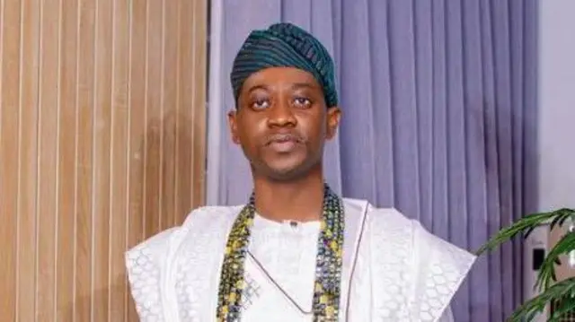 Lateef Adedimeji wọ agbada toke tilẹ funfun, o de fila asọ oke Ẹtu, o si fi ilẹkẹ pupọ sọrun