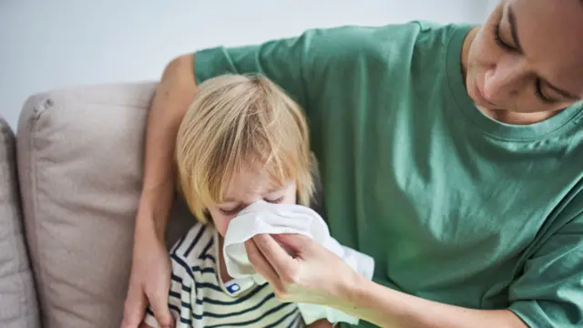Młoda matka wyciera nos dziecka białą chusteczką