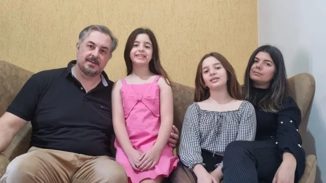 Bernardi ailesi birlikte bir kanepede oturmuş, kameraya gülümsüyor. Soldan sağa: Bruno Bernardi (Baba), Beatriz Bernardi (8), Lara Bernardi (10), Léia Bernardi (anne)