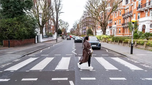 Pessoa atravessando a rua de uma cidade na faixa de segurança