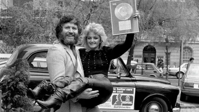 Una foto en blanco y negro de la entrega de un disco a Bonnie Tyler con el locutor de radio Dave Lee Travis en Londres en 1984.