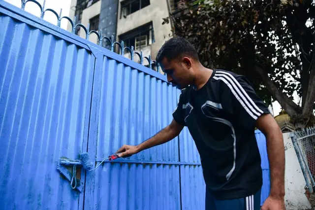 आन्दोलनका क्रममा तोडफोड र आगजनी गरिएको एउटा प्रहरी कार्यालयको ढोकामा रङ्गरोगन गर्दै एक प्रहरी जवान