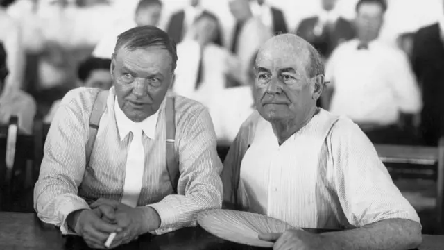 Dos hombres sentados uno al lado del otro en el tribunal, mirando al frente.