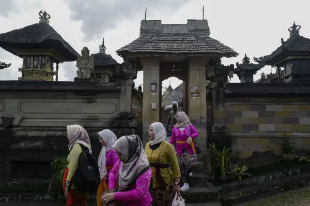 Wisatawan yang mengenakan pakaian adat mengunjungi Desa Penglipuran, Bali, Indonesia, pada juli 2024.