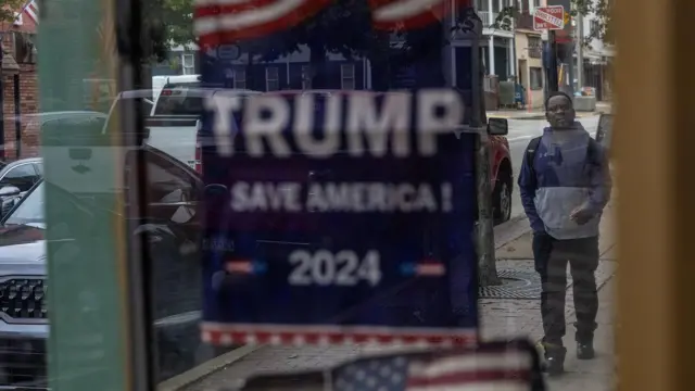 Homem caminha na calçada e,melhores site de apostaprimeiro plano, bandeira da campanhamelhores site de apostaTrump traz os dizeres 'Trump Save America'