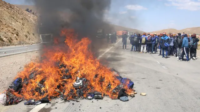 Una barricada de fuego bloquea parcialmente una carretera durante los enfrentamientos.