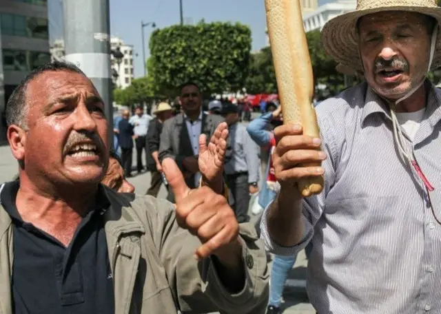 Manifestants exhibant un pain dans la rue