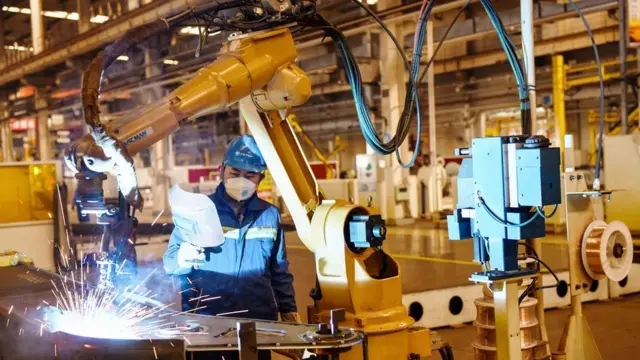 河北一家汽车工厂工人在生产线上带着口罩开工。