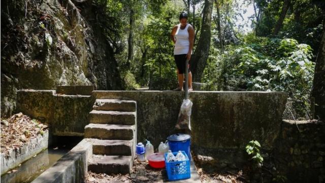 A woman looks at bottles and buckets filled with water from the mountain during blackouts, which affects the water pumps on March 12, 2019 in Caracas, Venezuela
